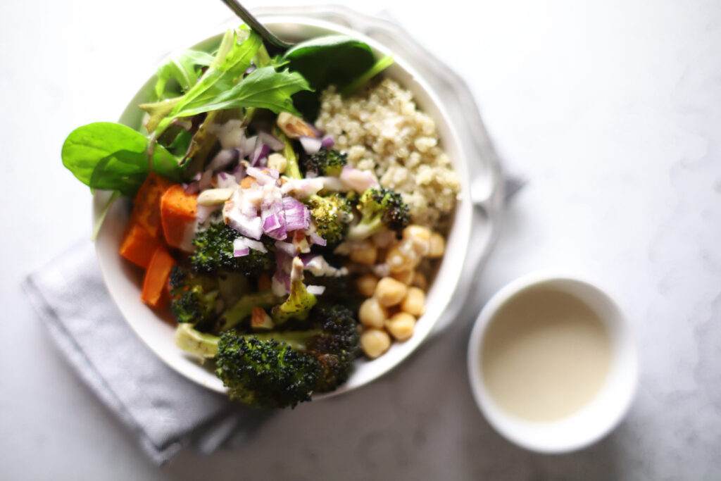 buddha bowl ingredients consisting of leafy green, chickpeas, quinoa, sweet potato