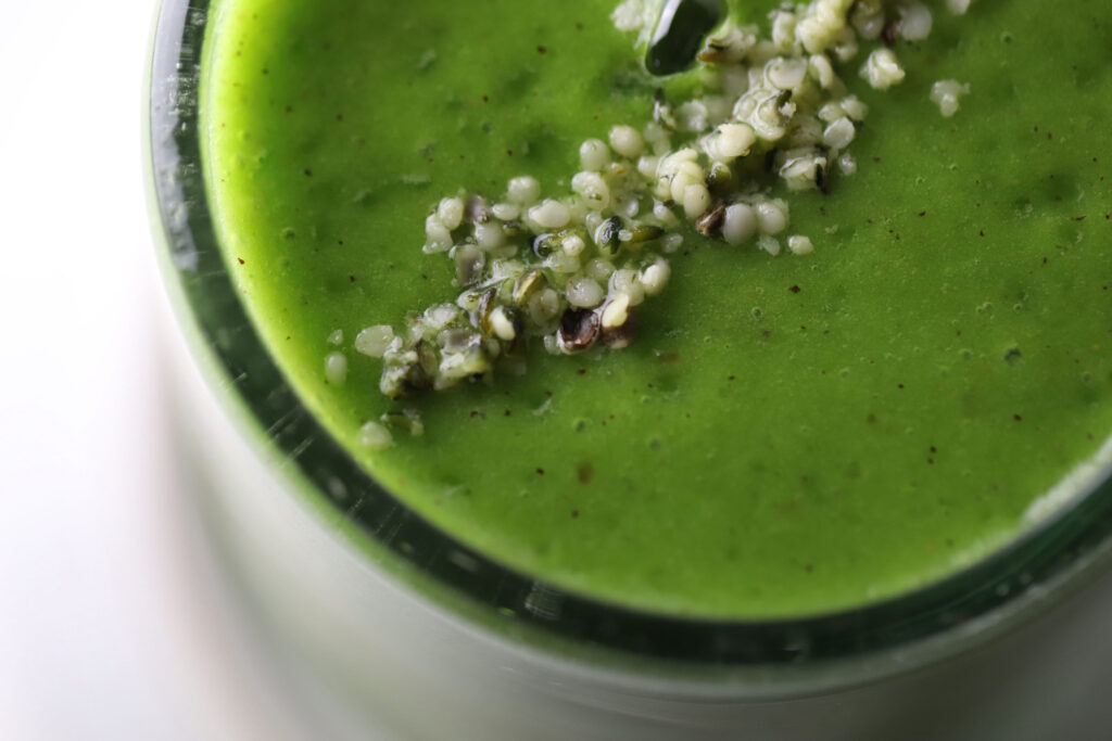 kiwi banana green smoothie in a glass topped with hemp hearts