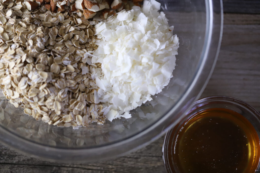 Ingredients to make toasted coconut honey granola in a glass dish