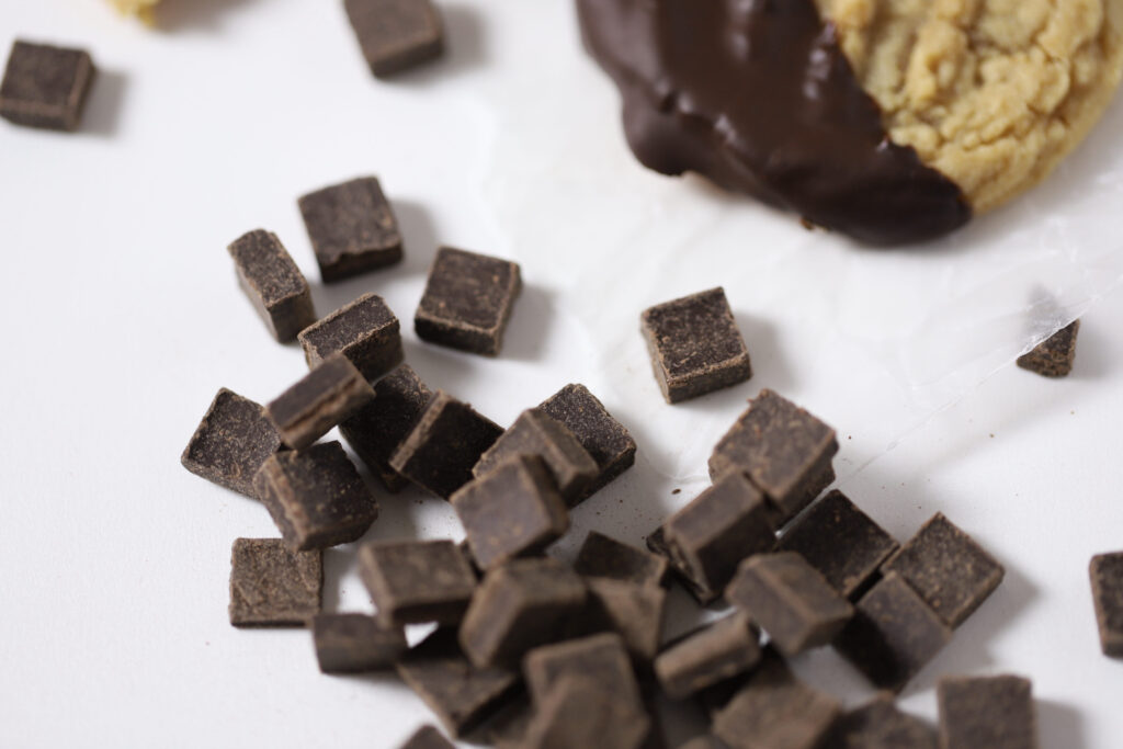 dark chocolate chips next to a peanut butter chocolate dipped cookie